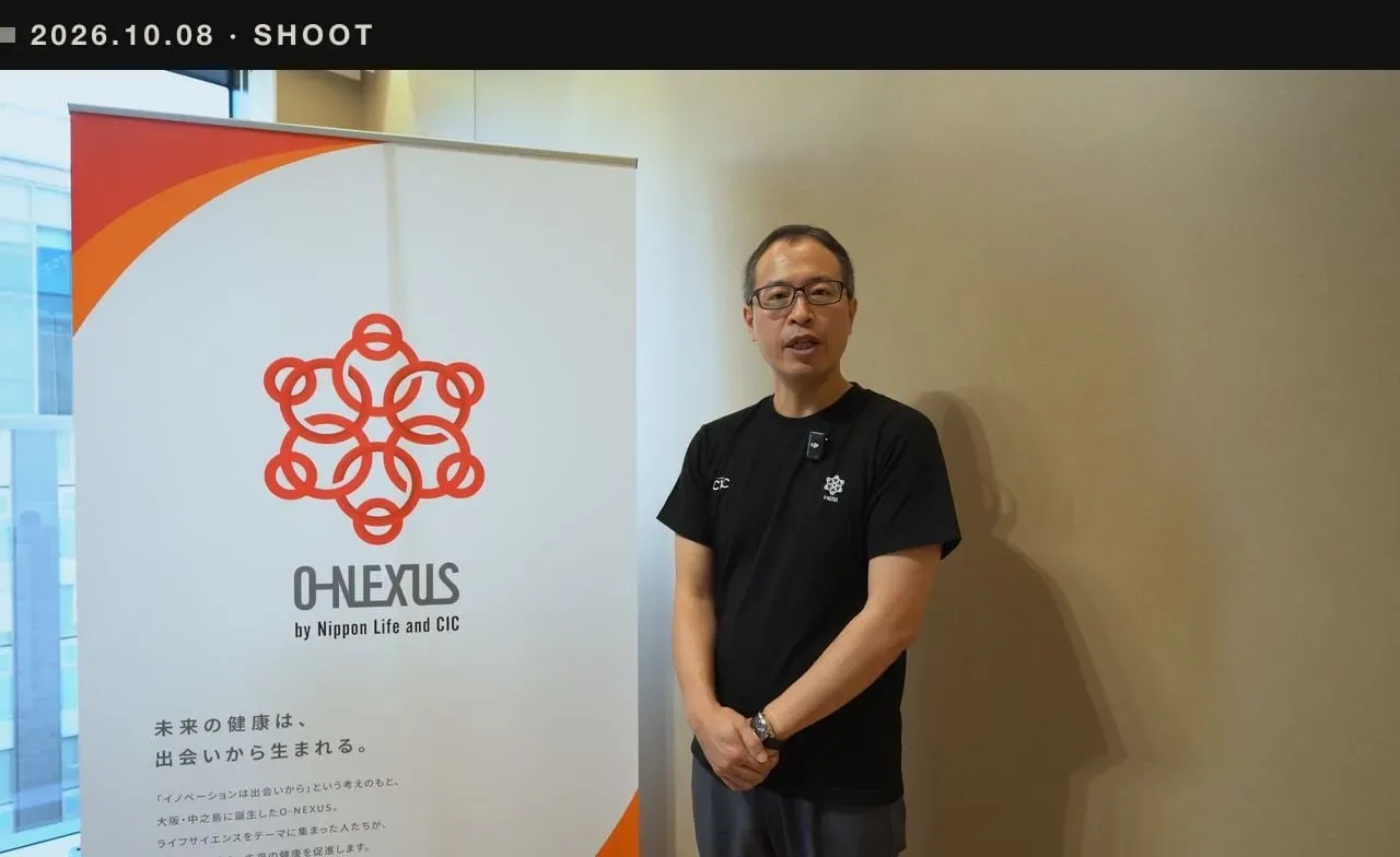 10月8日の撮影で、O-Nexusのバナーの横に立つ出演者